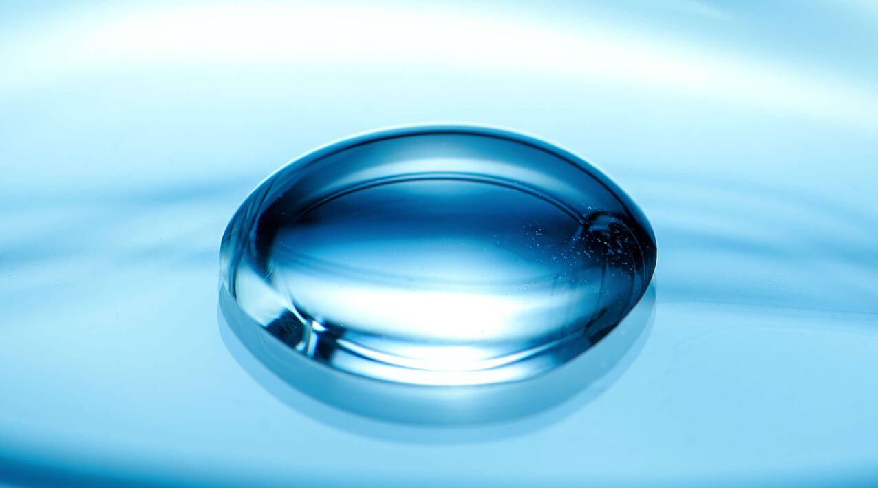 A single translucent high-purity droplet resting on a calm water surface